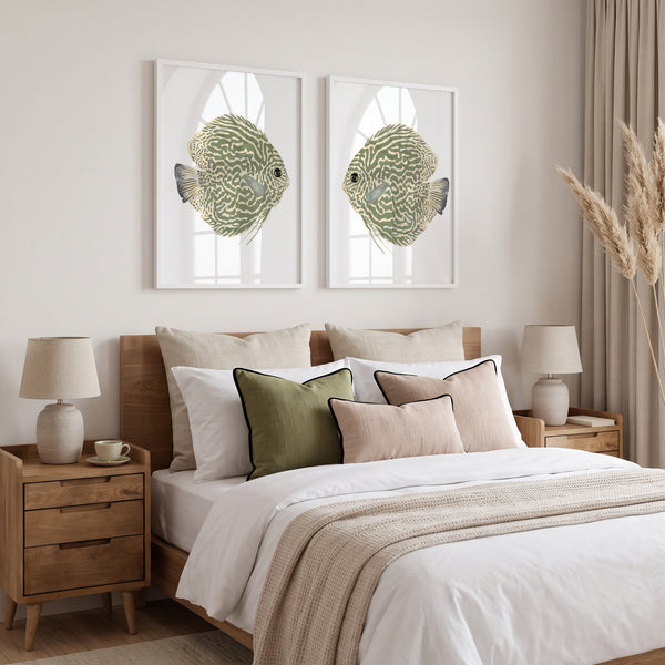 A styled bedroom scene with a wooden bed dressed in white bedding and accent pillows, flanked by matching bedside tables and lamps. Above the bed hang two framed wall art prints showing green patterned duscus fish on a white background.
