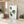 A watercolor painting of a green tropical leaf adds a touch of nature to a kitchen with a light colored countertop, wooden cabinets, and plants.