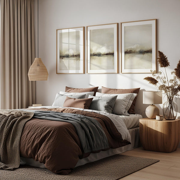 Neutral landscape wall art above a bed with brown and grey bedding