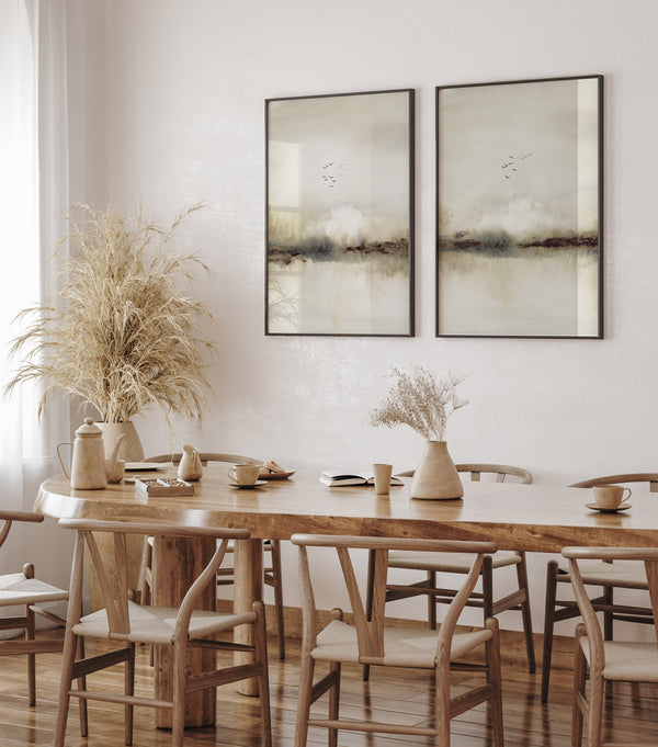 Beige watercolor landscape prints with birds in black frames above a wooden dining table