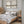 Two misty landscape prints with small black birds above a wooden bed in a panelled bedroom
