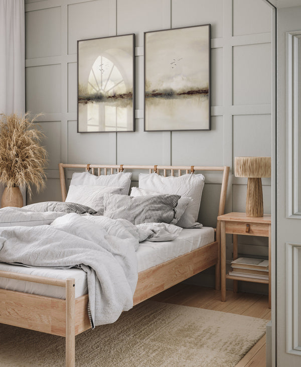 Two misty landscape prints with small black birds above a wooden bed in a panelled bedroom