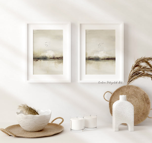 Neutral abstract landscape prints with birds in white frames above candles and a rattan tray