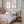 Watercolor paintings of minimalist large herons add a touch of nature to a bedroom with a bed, a nightstand, and a gray wall.