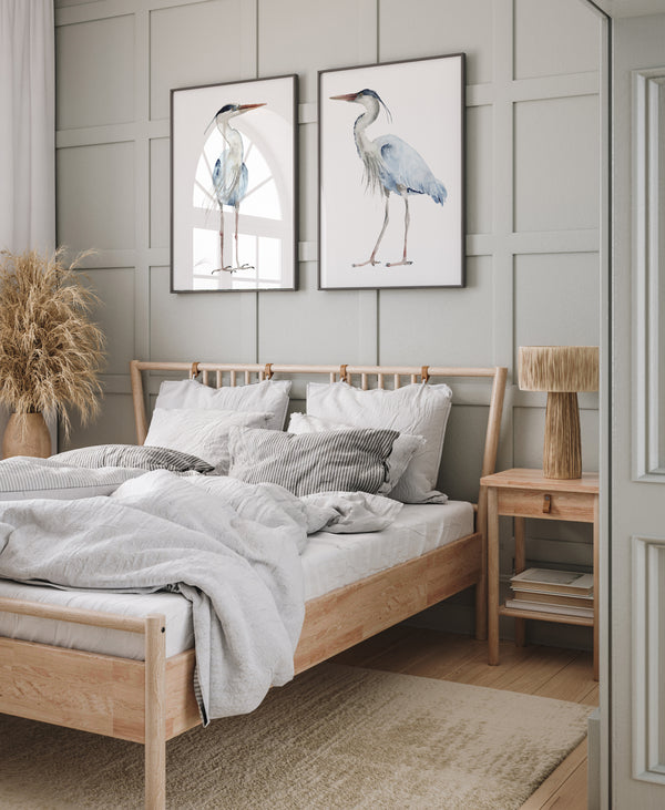 Watercolor paintings of minimalist large herons add a touch of nature to a bedroom with a bed, a nightstand, and a gray wall.