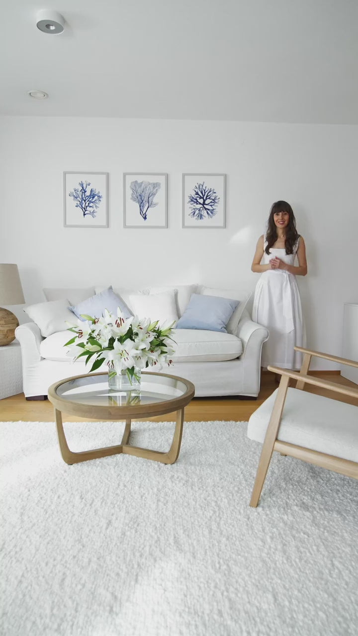 Eveline measuring coral watercolor prints in every size, from small to 80 cm, above a white sofa