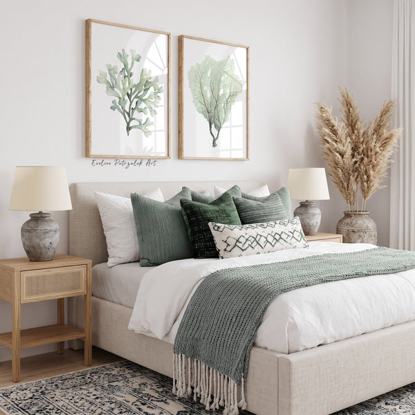 Sage green coral prints above a bed with green pillows and a knitted throw