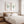 Two sage green coastal prints above a wooden bed with striped bedding