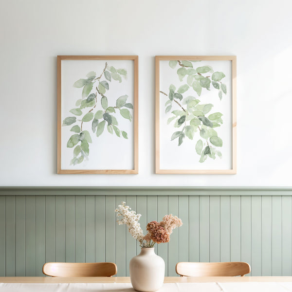 Sage green botanical prints above green wall panelling in a dining nook