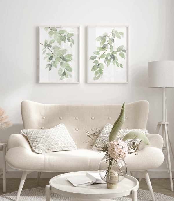 Sage green leaf branch prints above a cream boucle loveseat