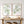 Watercolor sage green branch prints above a rustic wooden console with candles