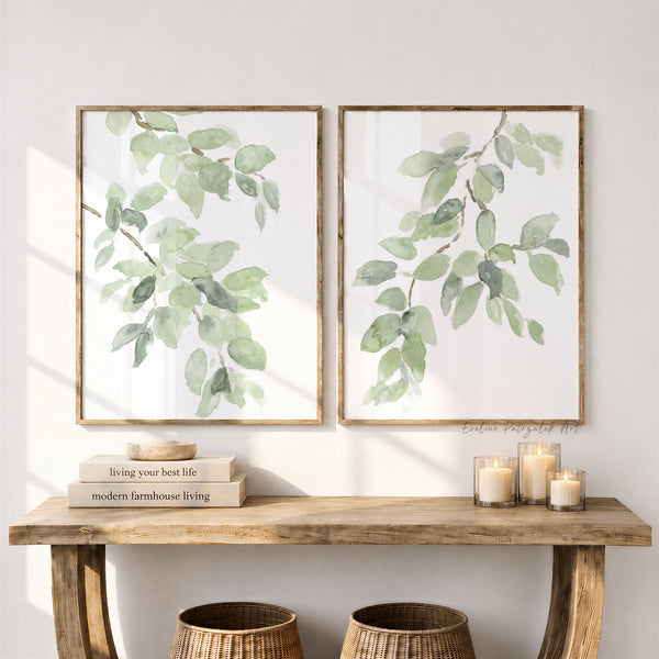 Watercolor sage green branch prints above a rustic wooden console with candles