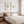 Two watercolor sea fan prints above a wooden bed with striped bedding