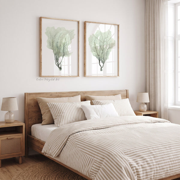 Two watercolor sea fan prints above a wooden bed with striped bedding