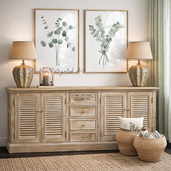 sage green eucalyptus prints in wooden frames hang above a wooden console 