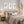 A styled bedroom scene featuring a bed with neutral-toned bedding, a woven cane headboard, matching bedside tables and lamps, three framed botanical prints on the wall, and dried pampas grass decor.