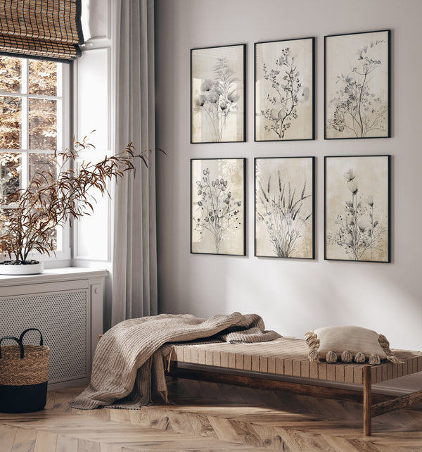 Six framed botanical prints featuring delicate black wildflowers against a textured, tan background. The prints are arranged in a grid on a wall above a bench in a cozy living space.