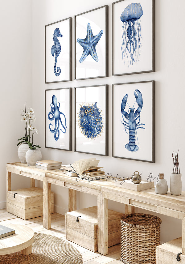 Nautical-themed wall art prints in a home interior setting. art hanging above low wooden console - wall art featuring navy blue sea creatures including minimalist watercolor jellyfish, starfish, lobster, seahorse, octopus and puffer or so called diodon fish.