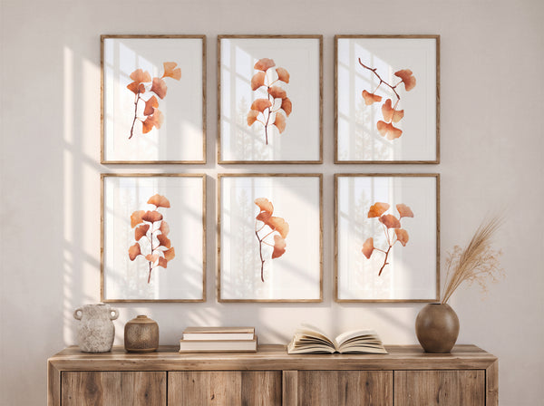 Six framed botanical prints featuring orange-brown ginkgo leaves on a white background, arranged in a 2x3 grid on a beige wall above a wooden console table with books and decorative vases.