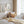 Vintage wildflower prints above a white bed with a rattan chair and natural linen