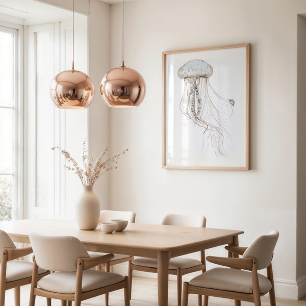 Neutral jellyfish wall art in a light wood frame above a dining table with copper pendant lamps