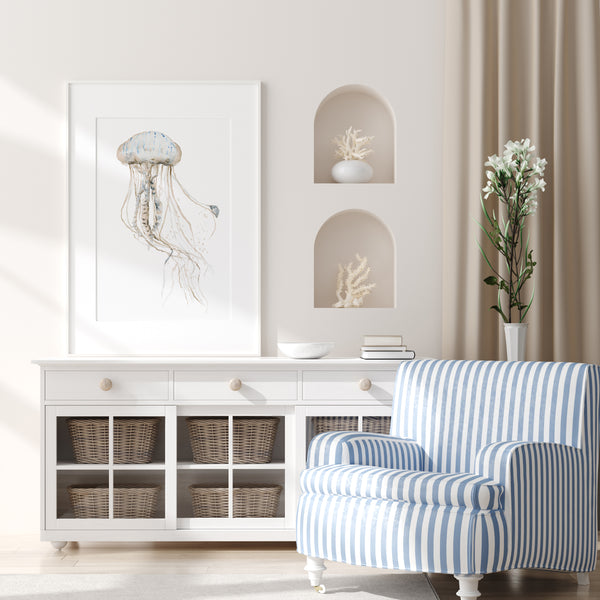 Sand beige jellyfish painting above a white sideboard next to a blue striped armchair