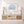 Nautical-themed room with a wooden console table, framed crab art, and decorative items.