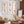 Six framed botanical prints of orange-gold ginkgo leaves arranged in a 2x3 grid on a light gray wall in a modern living room with brown furniture and woven decor.