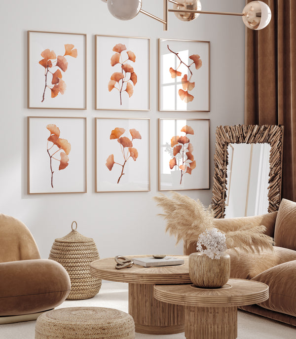 Six framed botanical prints of orange-gold ginkgo leaves arranged in a 2x3 grid on a light gray wall in a modern living room with brown furniture and woven decor.