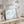 Framed artwork of birds flying in a sky with clouds on a wooden surface, surrounded by decorative items.