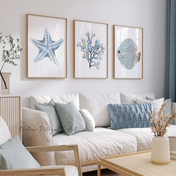 Living room with a white sofa, decorative pillows, and framed artwork with 3 wooden frames containgin artwork of a minimalist starfish, coral, and fish.