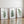 Three framed botanical art prints with green fern leaf illustrations leaning against a white wall on a polished wood floor.