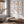 Six framed botanical prints featuring orange-gold ginkgo leaves arranged in two columns on a light gray wall above a wooden bench in a styled room with a window, curtains, and a throw blanket.