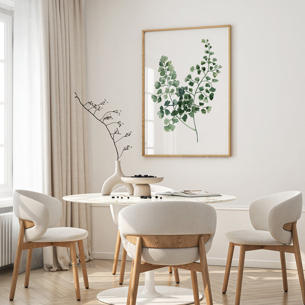 A framed watercolor painting showcases the intricate details of a green fern, creating a calming and elegant atmosphere in a dining room with a round table and upholstered chairs.