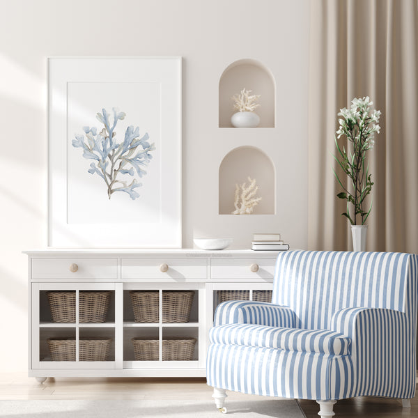 Light blue watercolor coral print above a white cabinet next to a striped armchair