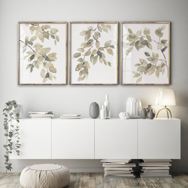 Watercolor paintings featuring delicate branches and leaves in soft shades of green and brown. The paintings are framed and displayed on a white wall above a modern console table.