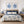 Bedroom with dark blue floral bedding, blue lamps, and navy blue minimalist wall art showing set of 2 blue corals painted against white background and in wooden frames